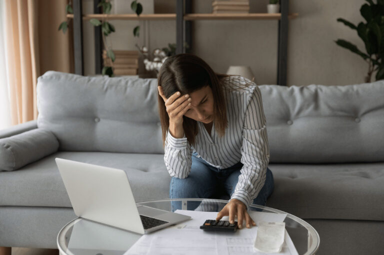 A stressed woman looks at document and her calculator