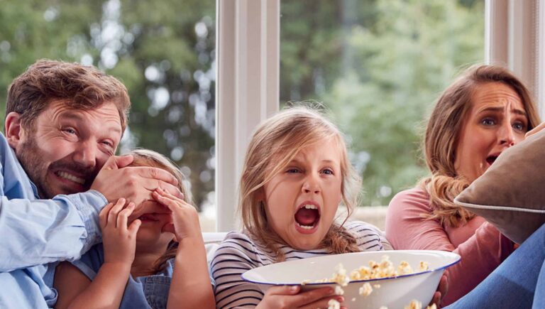 A family watching a scary movie and eating popcorn