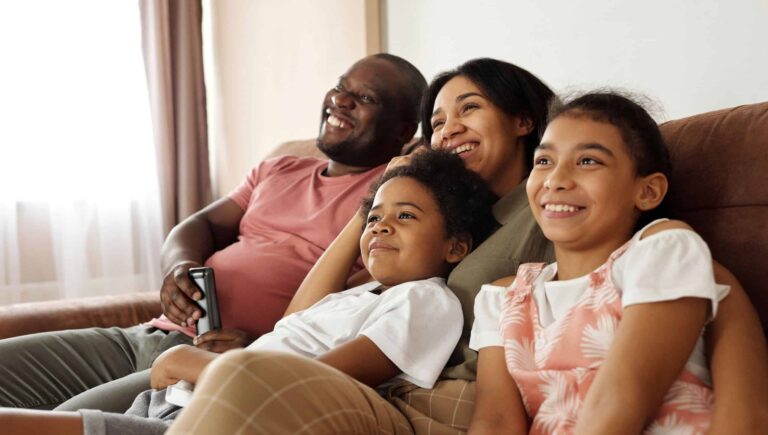 A happy family sitting on couch watching television