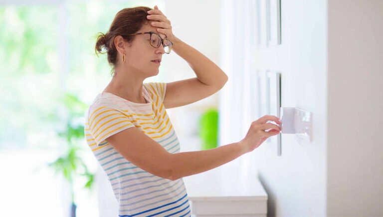 A woman adjusting her thermostat