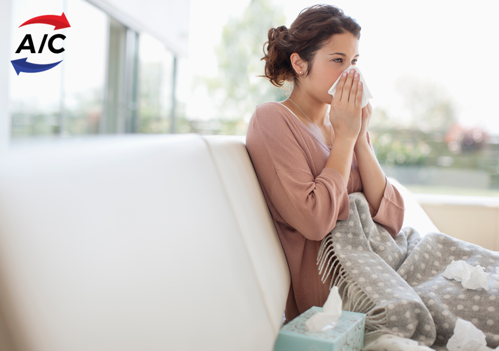 A woman in a bright, sunlit room blowing her nose
