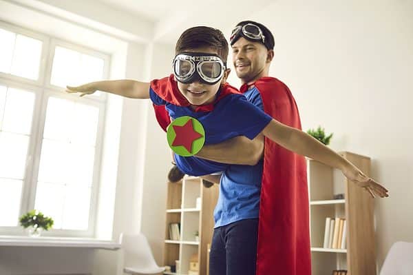 A father and son dressed as superheroes playing