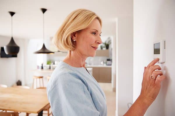 A woman adjusting her home thermostat