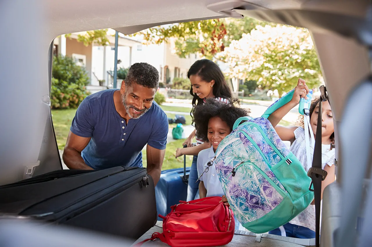 Family Leaving For Vacation Loading Luggage Into Car