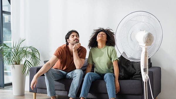 A Couple sitting on their couch in front of a fan