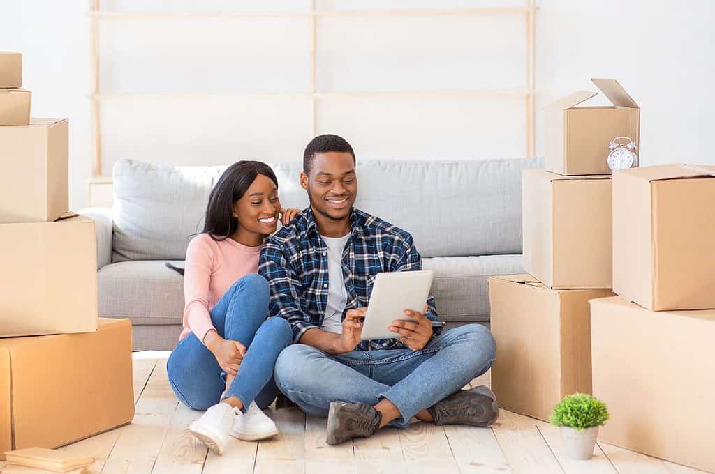 New homeowners sit on the floor surrounded by moving boxes