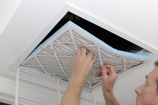 person removing dirty air filter from vent